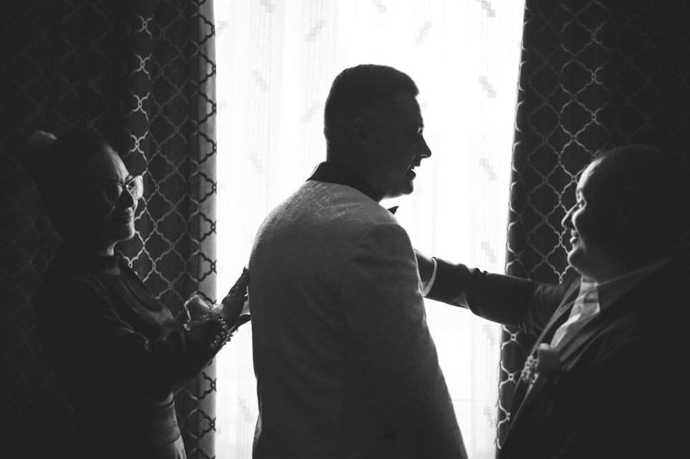 a black and white photo of a man adjusting another man's tie