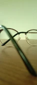 Close-up of vibrant blue and green eyeglass frames resting on a wooden table.
