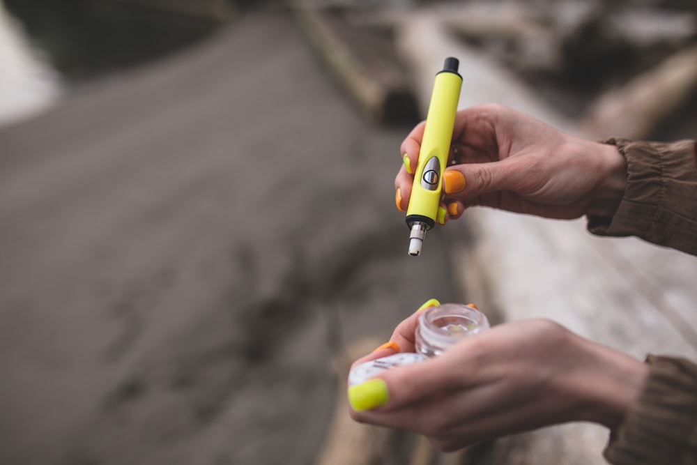 a person is holding a yellow and black pen