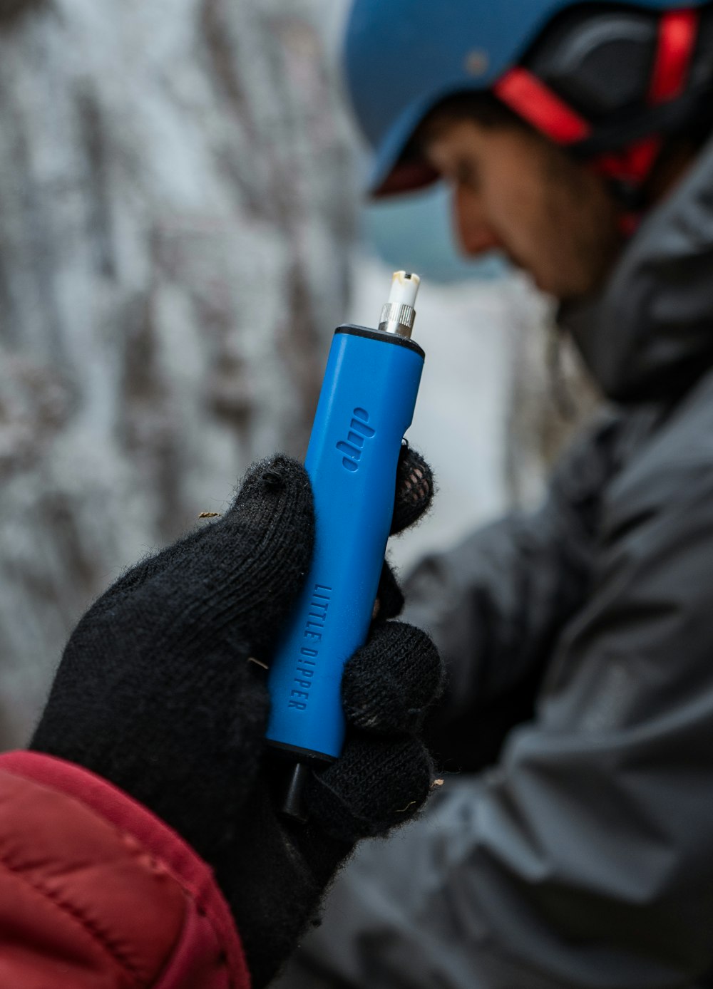 a person holding a blue lighter in their hand