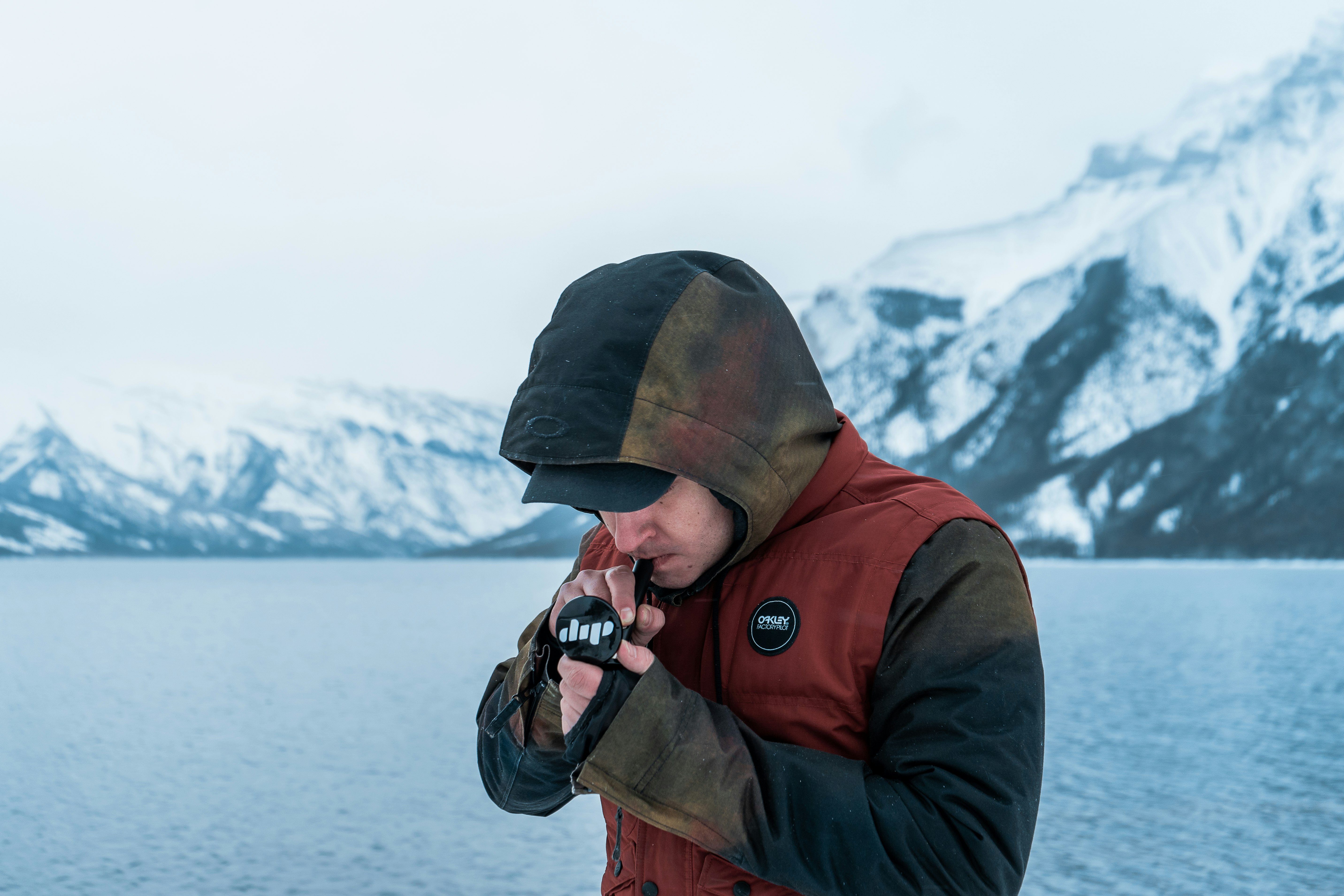 A man stands by the waterside smoking a black Dip Devices Little Dipper concentrate vaporizer dab straw outdoors. He wears a vest over a jacket and is framed by snowy mountains.

See more at https://dipdevices.com/ 