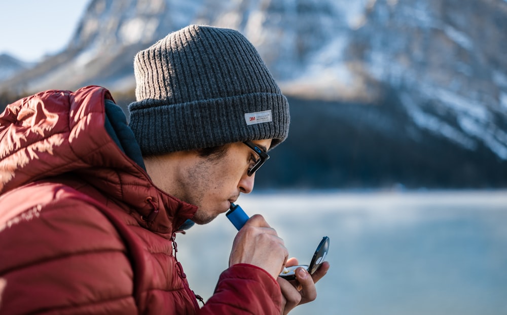 a man wearing a beanie and using a cell phone