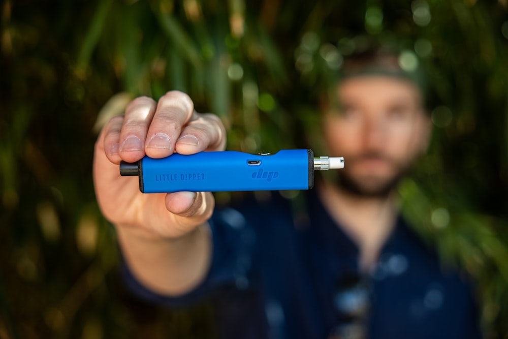 a man holding a blue electronic device in his hand