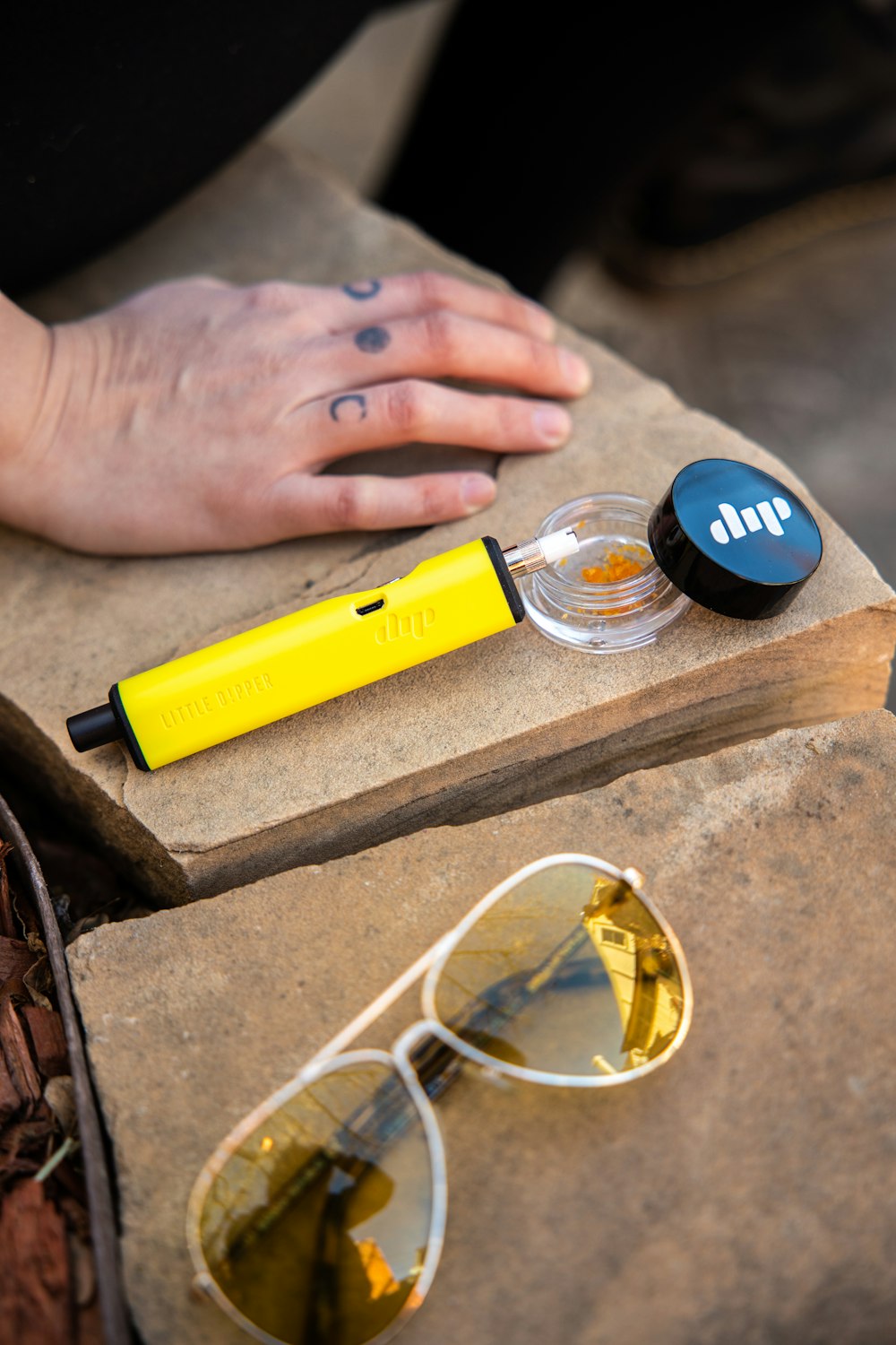 la main d’une personne avec une bague et des lunettes de soleil