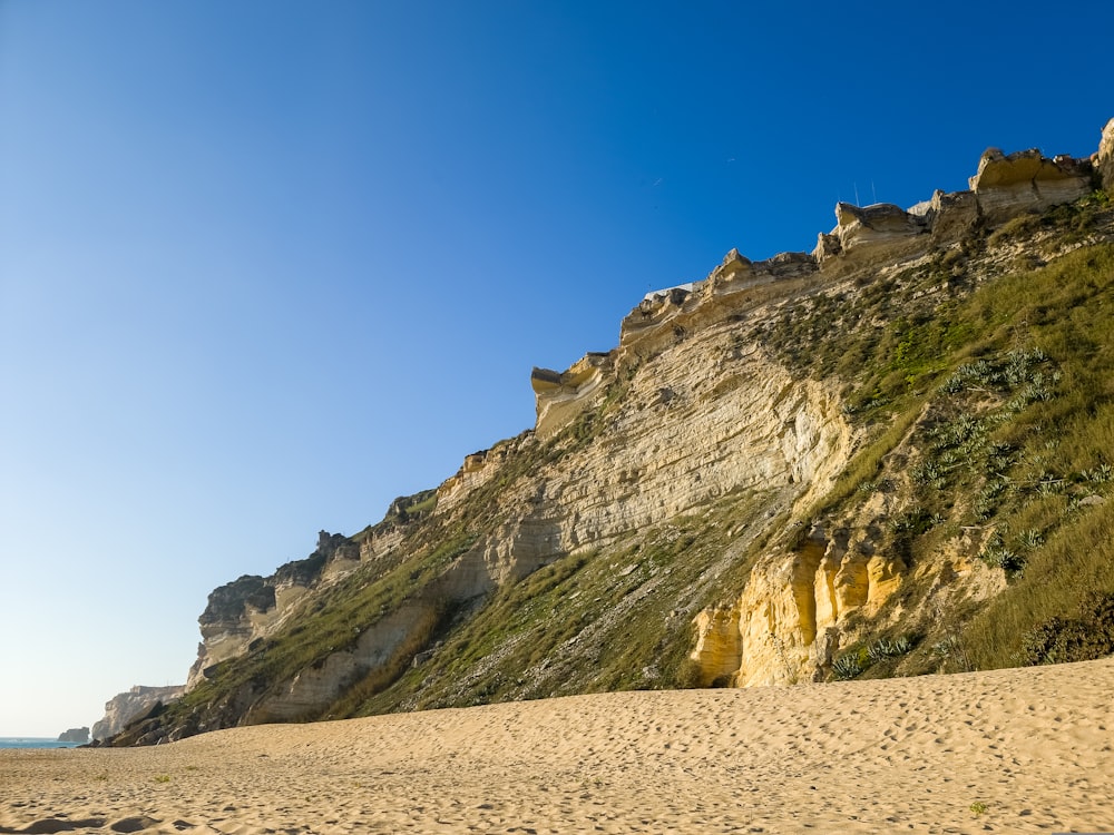 a sandy beach with a cliff in the background