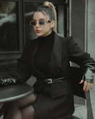 A stylish woman sitting at a café table wearing a sleek black top.