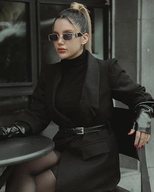A stylish woman sitting at a café table wearing a sleek black top.