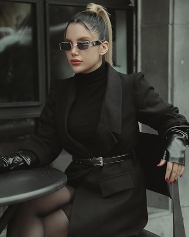 a woman sitting at a table wearing a black outfit