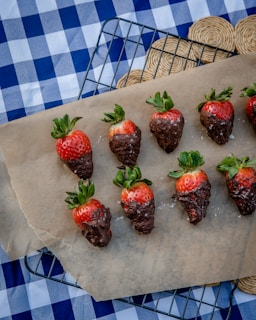 Freshly dipped chocolate strawberries cooling on a wire rack in a cozy kitchen.