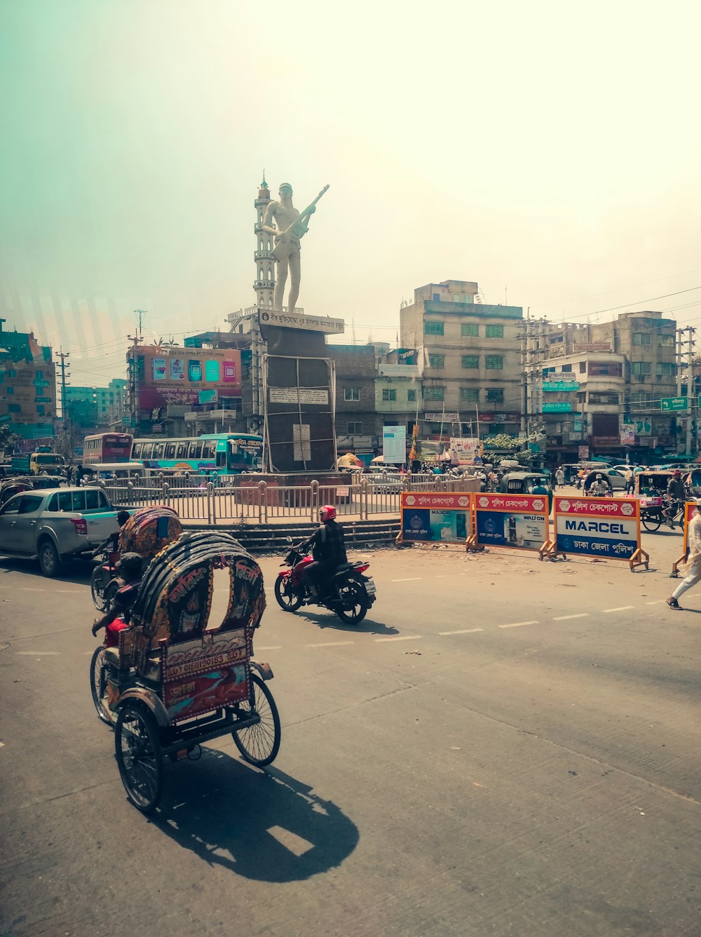 a man riding a motorcycle down a street next to a statue