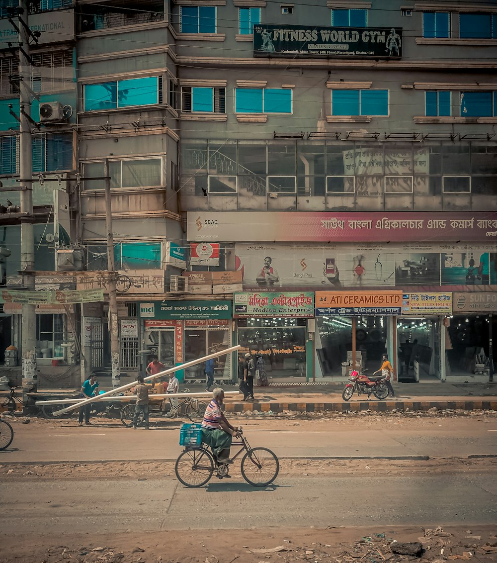 a man riding a bike down a street next to a tall building