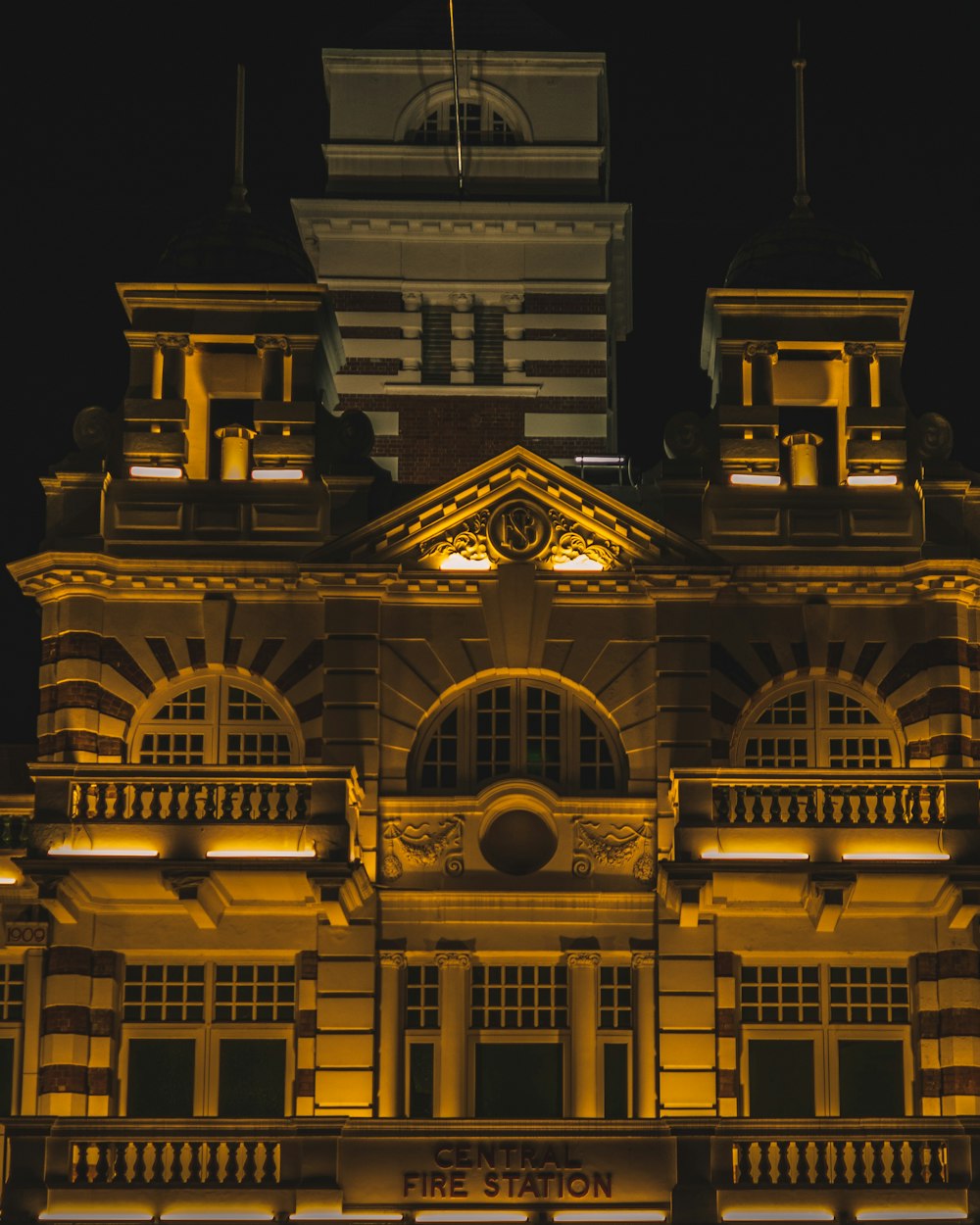 a building lit up at night with a clock tower in the background