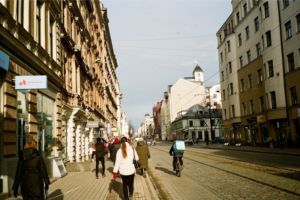 a group of people walking down a street next to tall buildings