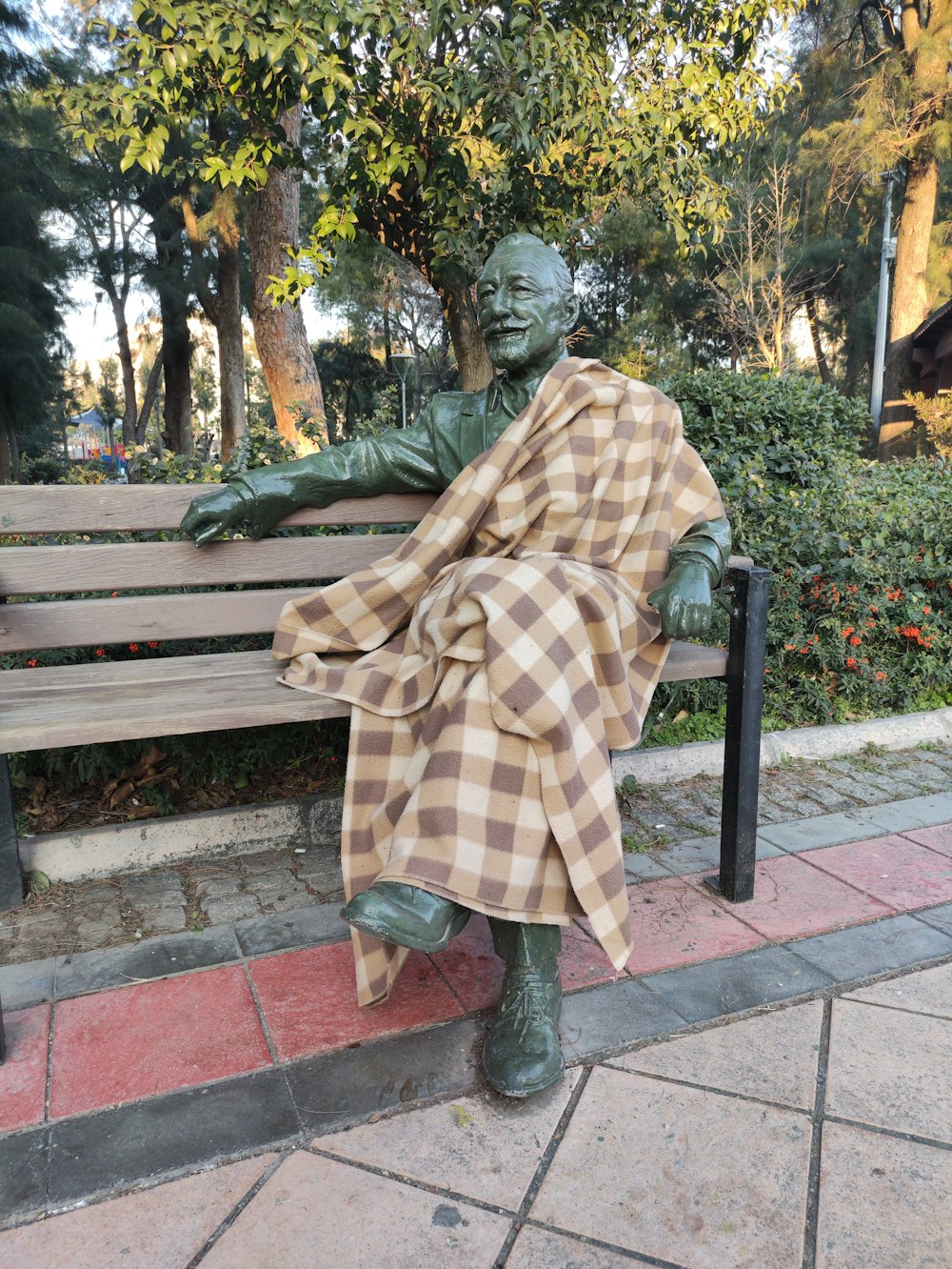 uma estátua de um homem sentado em um banco de madeira