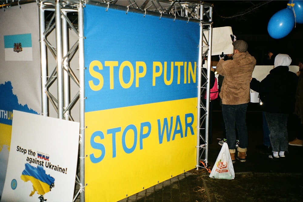 a group of people standing around a blue and yellow sign