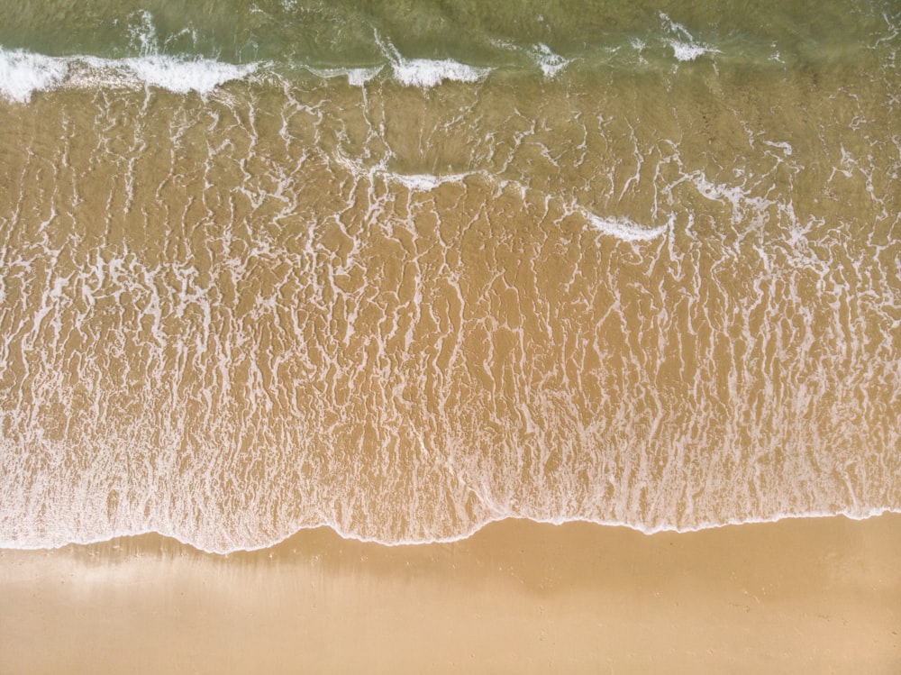 an aerial view of a sandy beach with waves