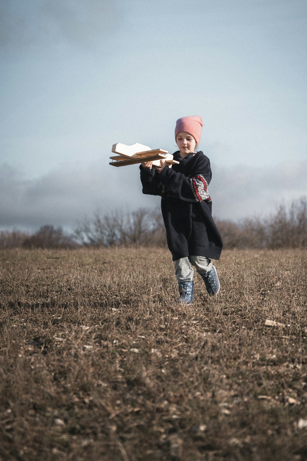 Una niña corriendo por un campo sosteniendo un bate