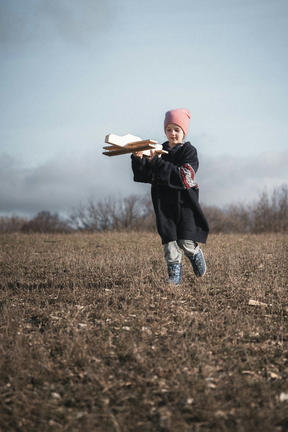 a little girl running across a field holding a bat