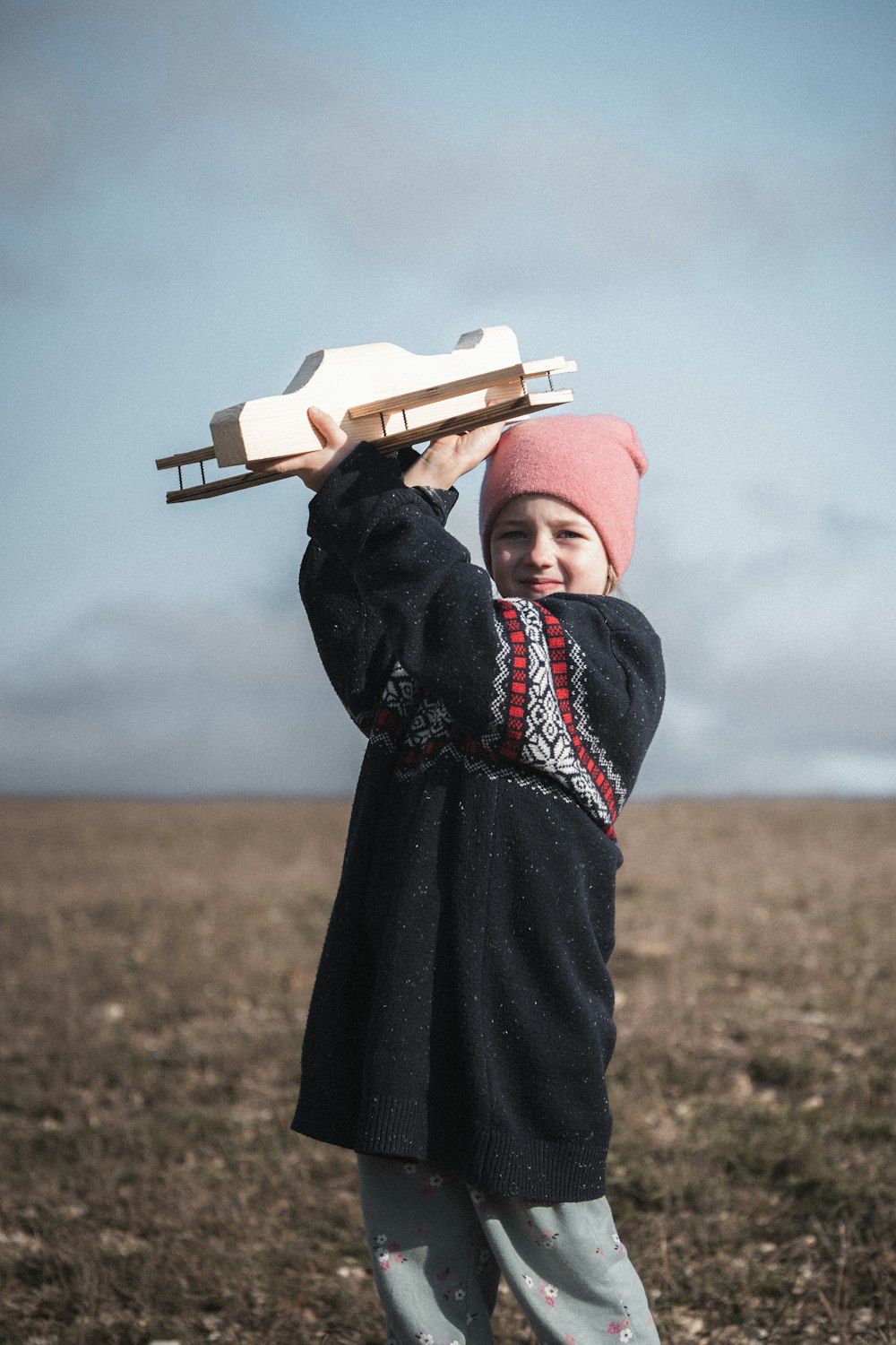 Una niña sosteniendo un trineo de madera en su cabeza