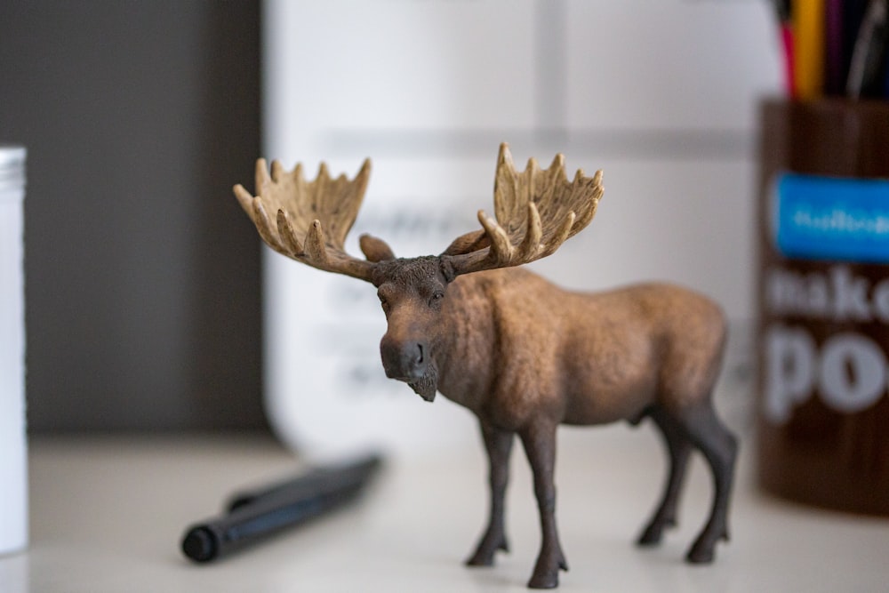a toy moose standing on a desk next to a pen