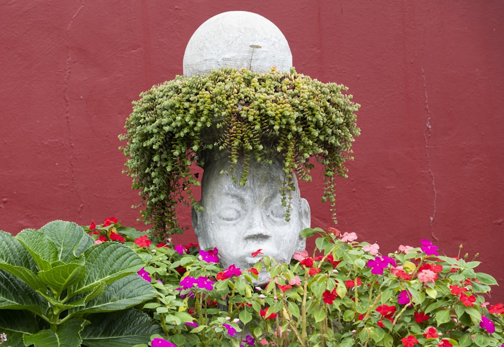 a statue of a head surrounded by flowers