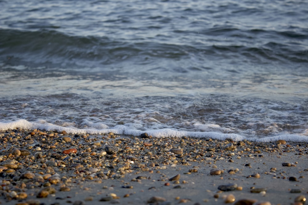 a close up of a beach with a wave coming in