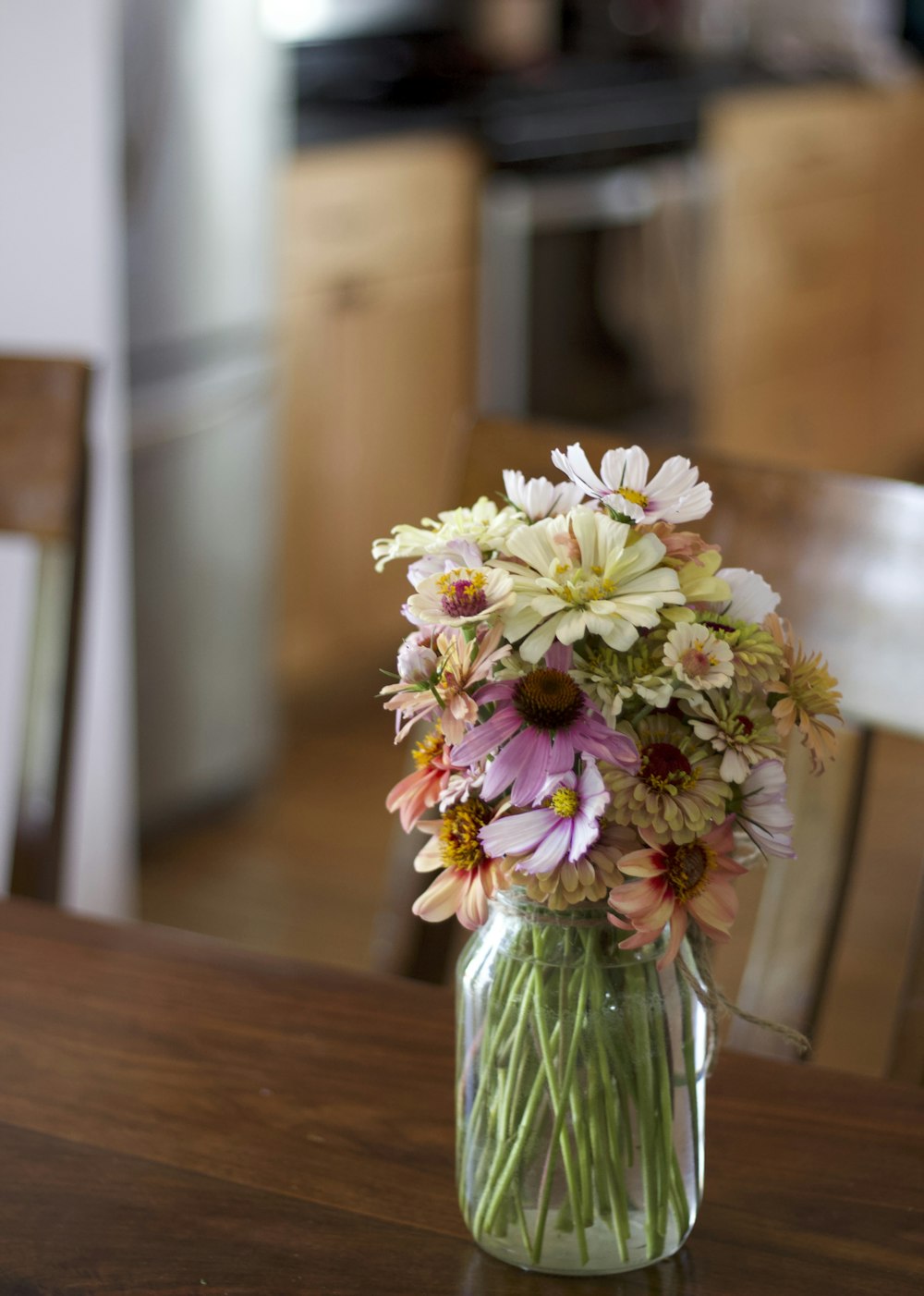 um vaso cheio de muitas flores em cima de uma mesa de madeira