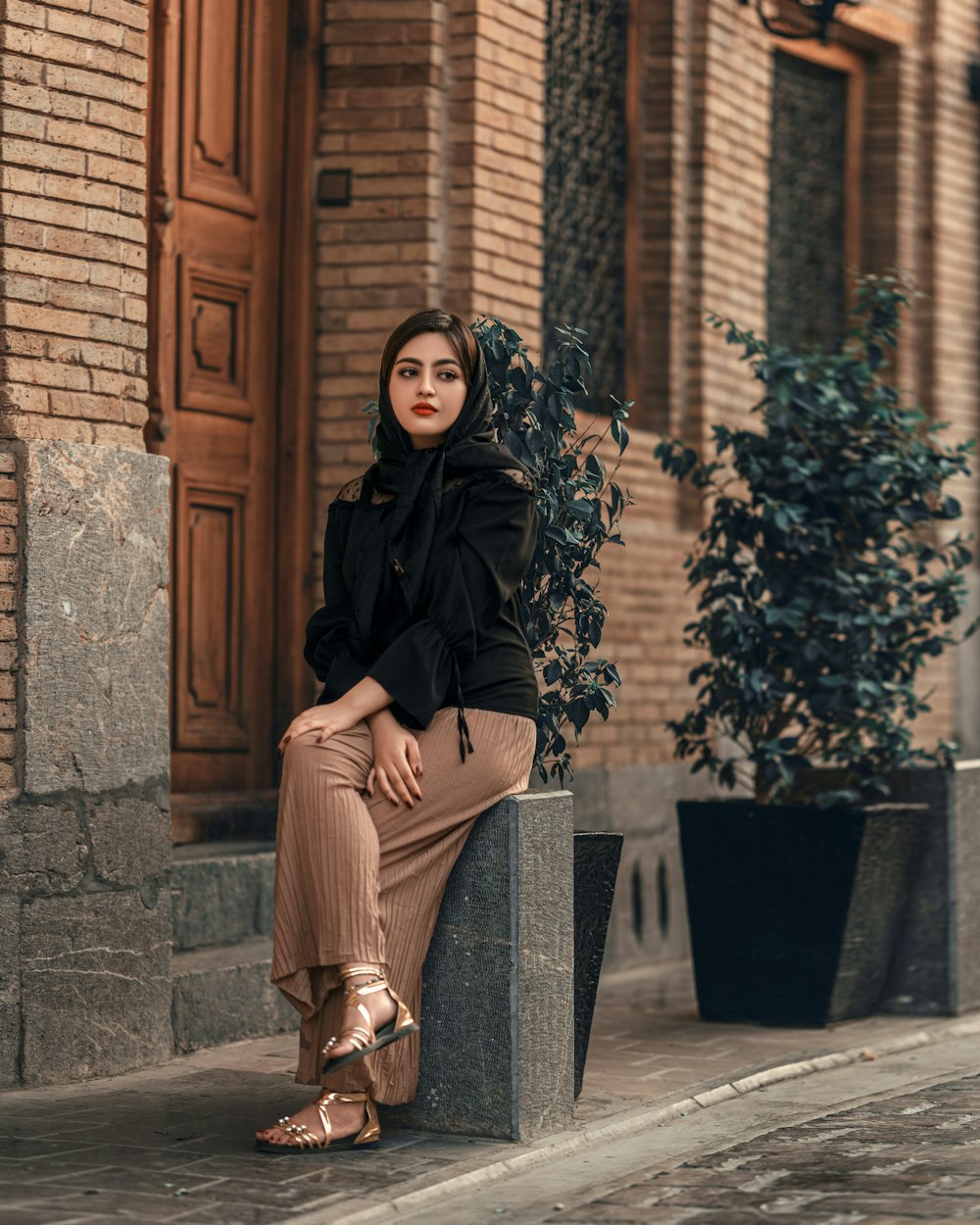 a woman is sitting on a block outside a building