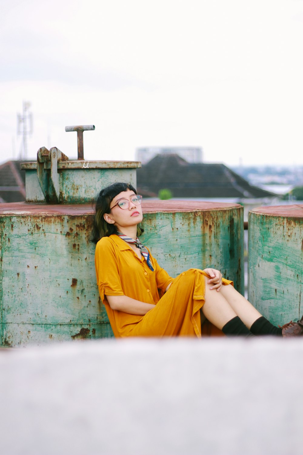 a woman in a yellow shirt and tie sitting on a wall