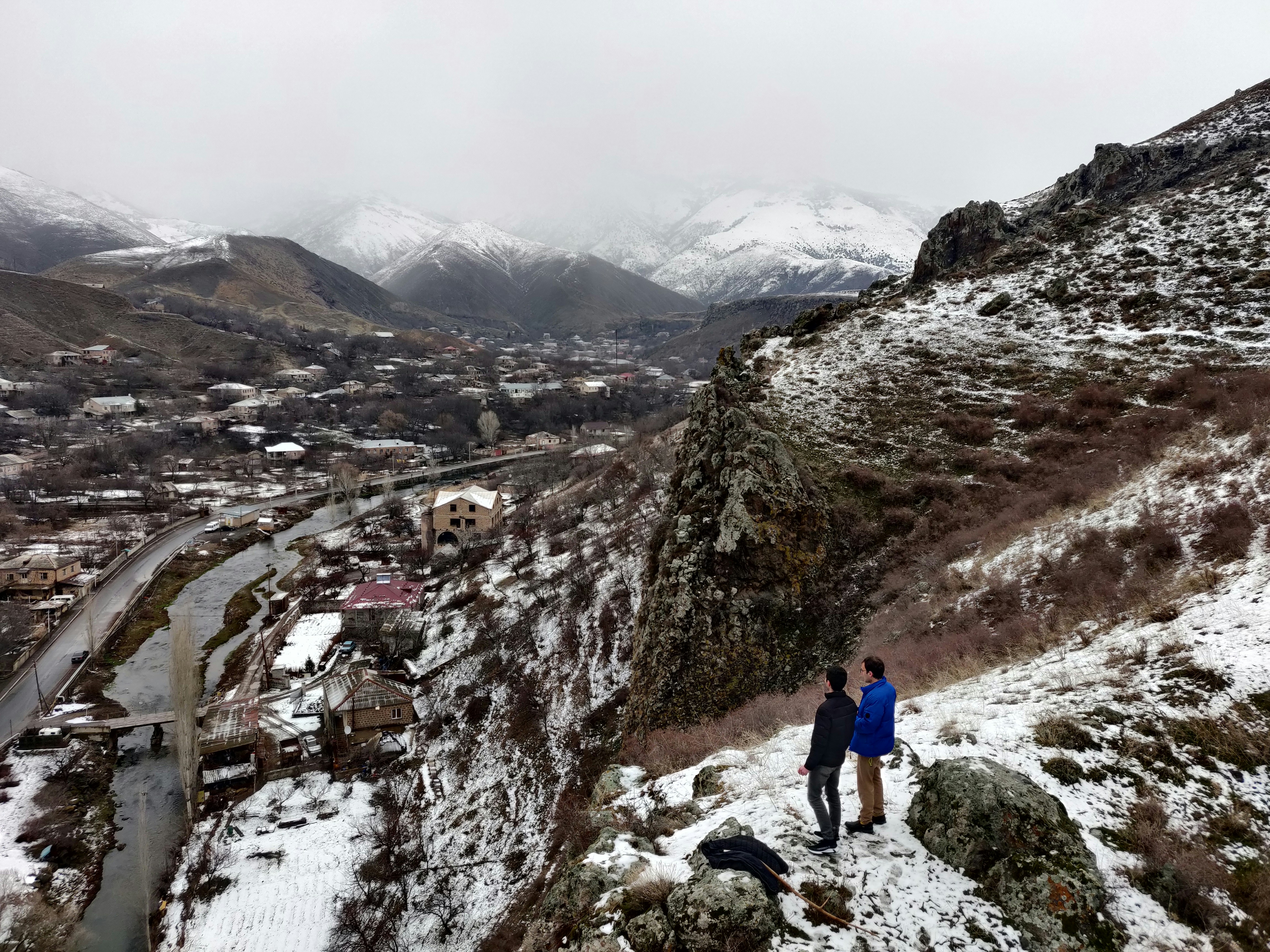a couple of people standing on top of a snow covered hill