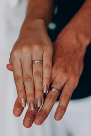 A couple holding hands, showcasing their matching custom wedding rings