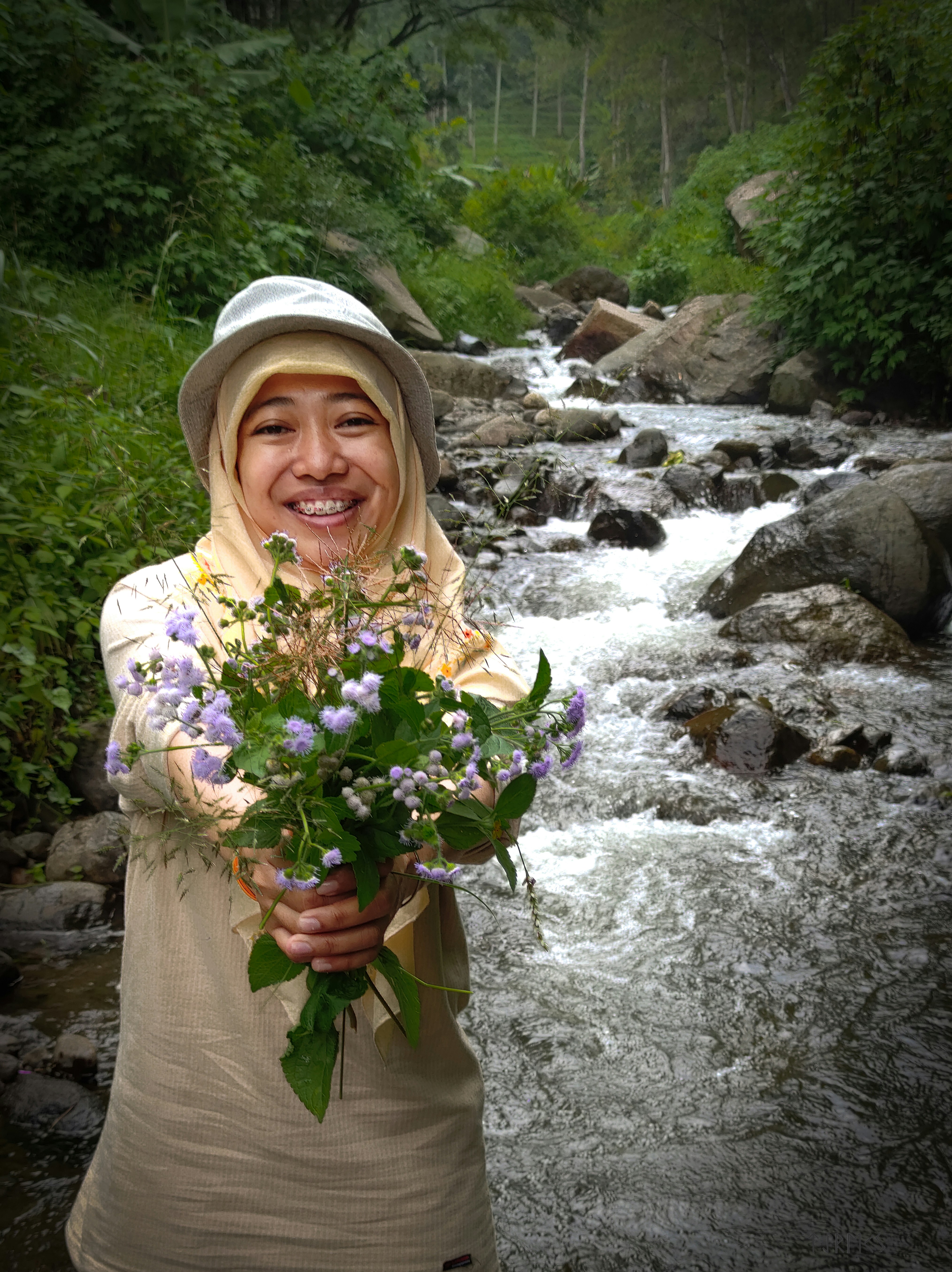 a woman holding a bouquet of flowers in front of a river