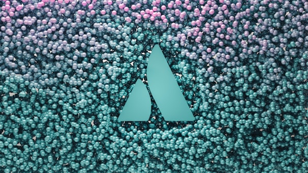A geometric logo with two triangular shapes is embedded in a backdrop of numerous small spherical objects that transition from teal at the bottom to pink at the top.