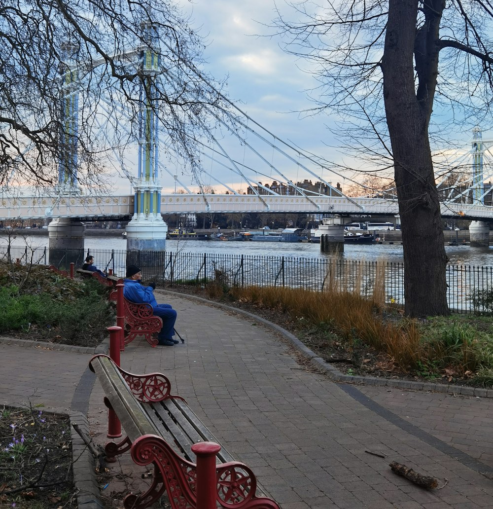 a man sitting on a bench next to a river