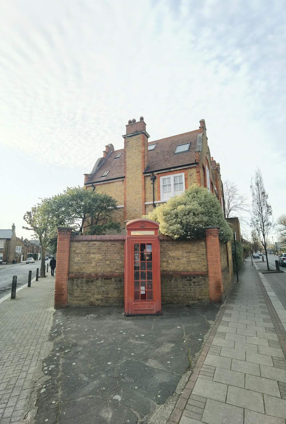 a red phone booth sitting in front of a brick building