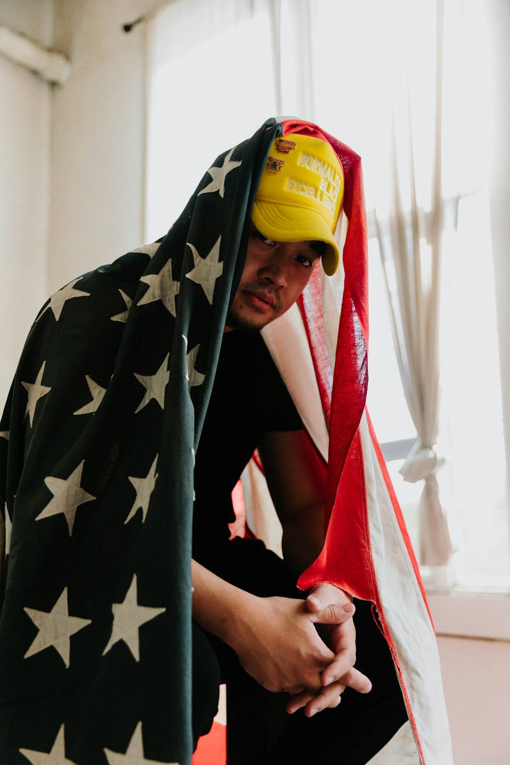 a man in a yellow hat hiding behind a flag