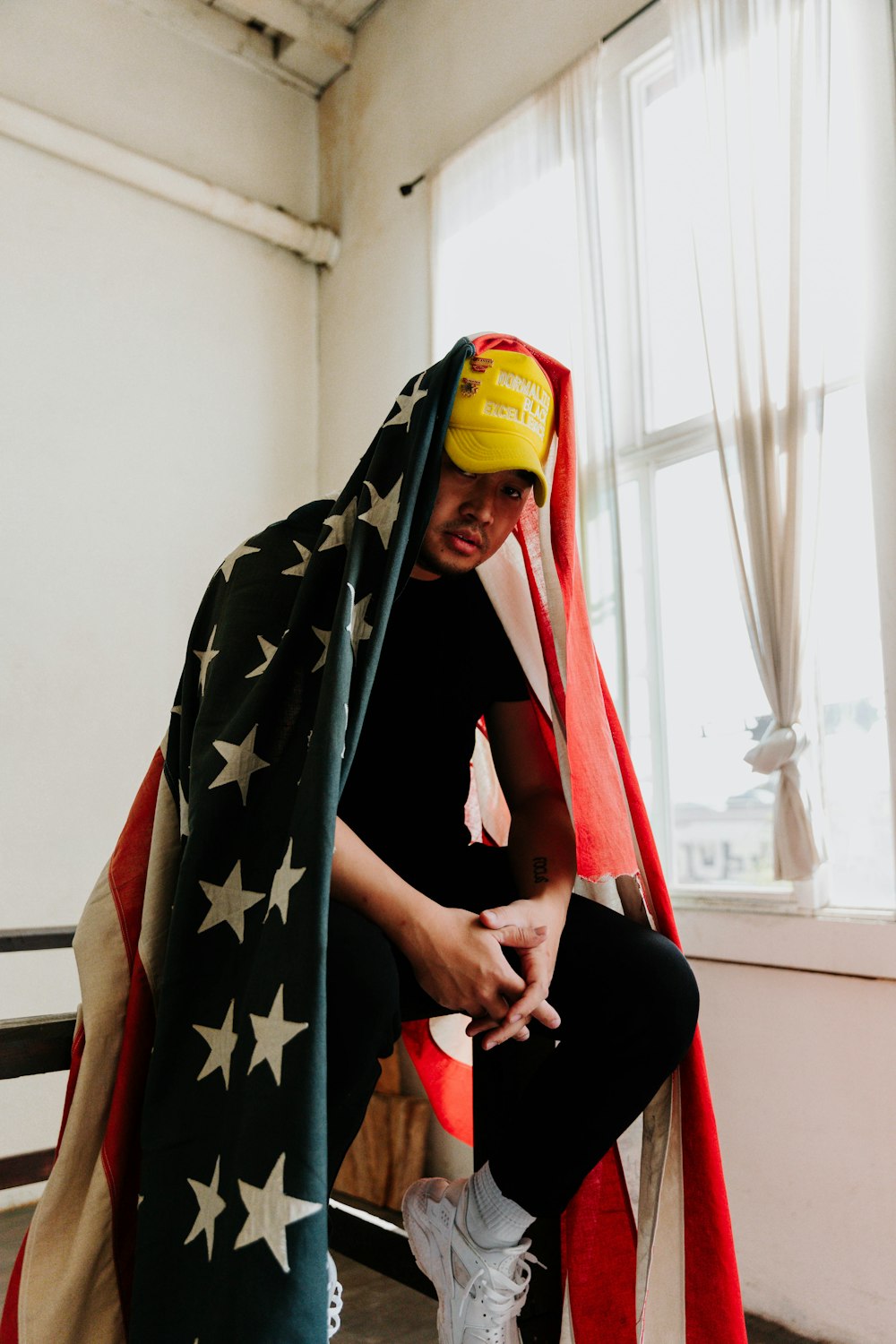 a man sitting on a bench with an american flag draped over his head