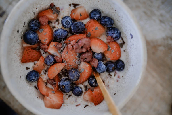 A colorful bowl of fresh berries topped with sliced almonds on a rustic wooden table.