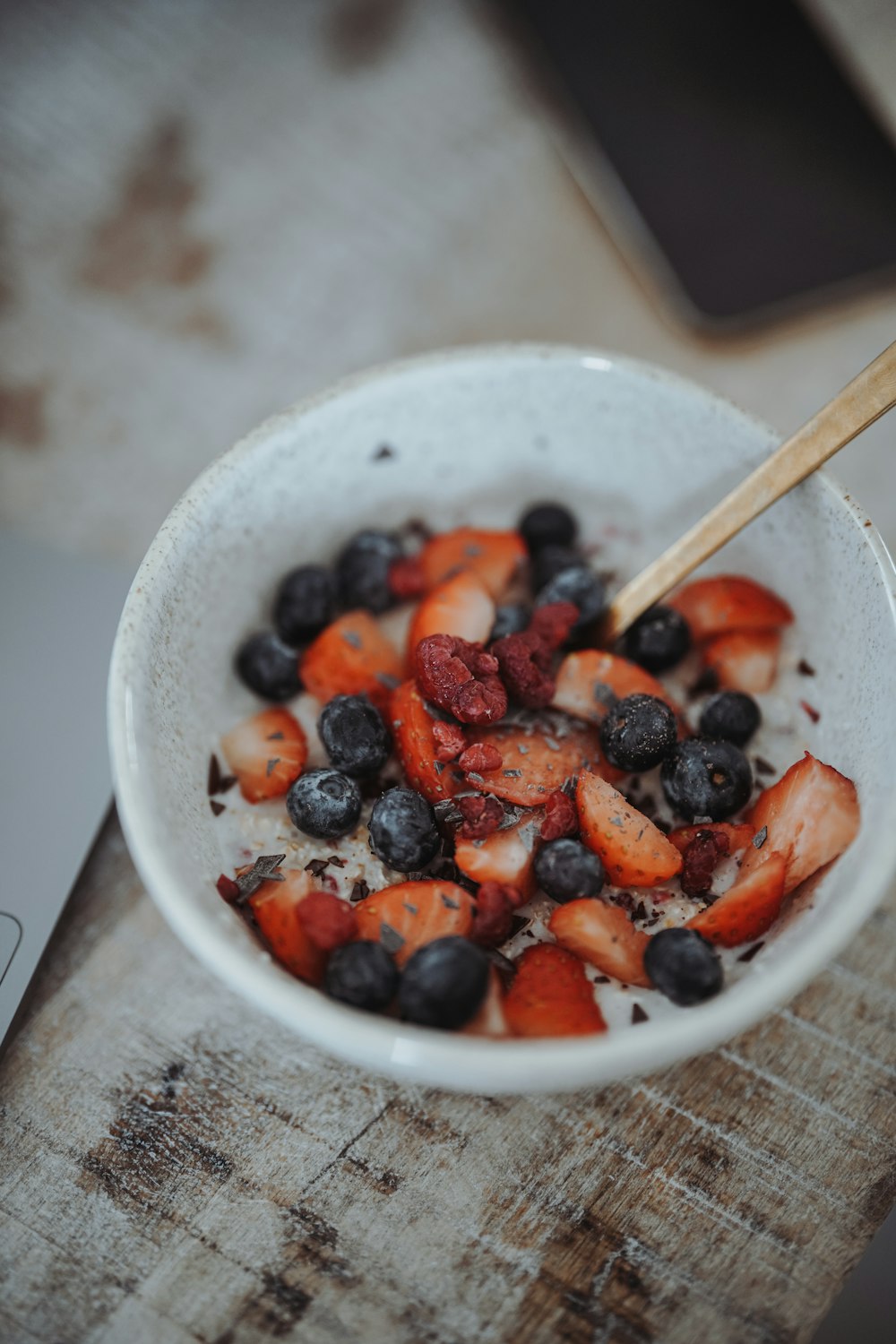 a bowl of berries and strawberries with a wooden spoon