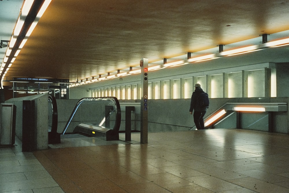 a man is walking through an airport with an escalator