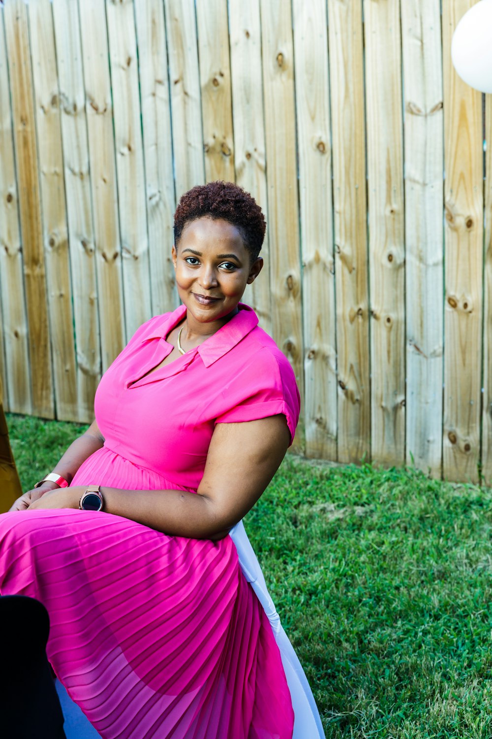 a woman in a pink dress sitting in the grass