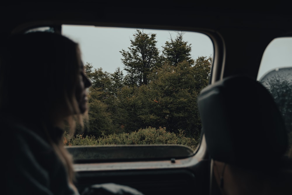 a woman sitting in a car looking out the window