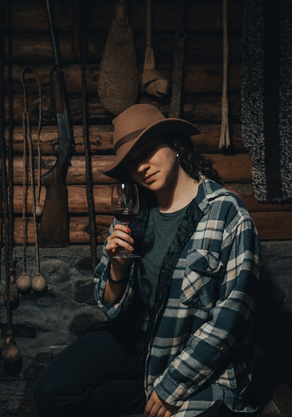 a woman wearing a hat and holding a glass of wine