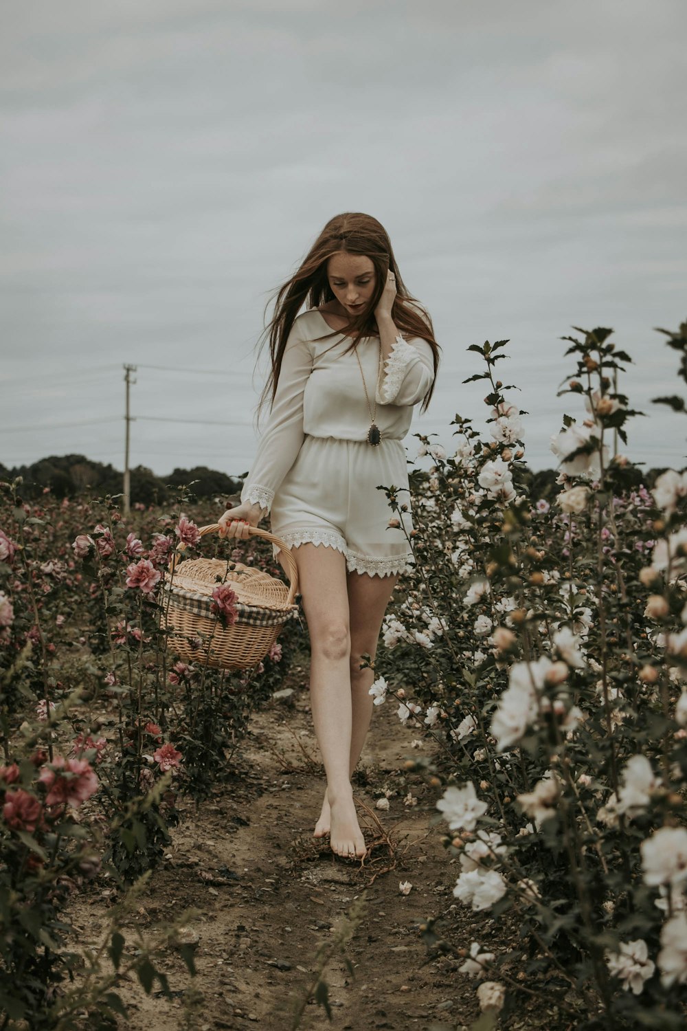 a woman walking through a field of flowers