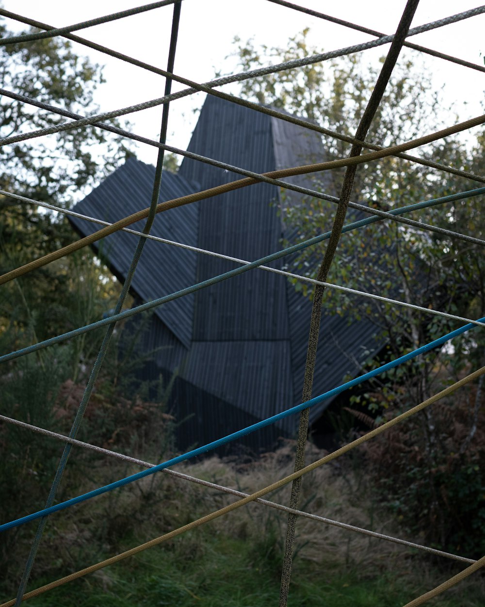 a black building is seen through a wire fence