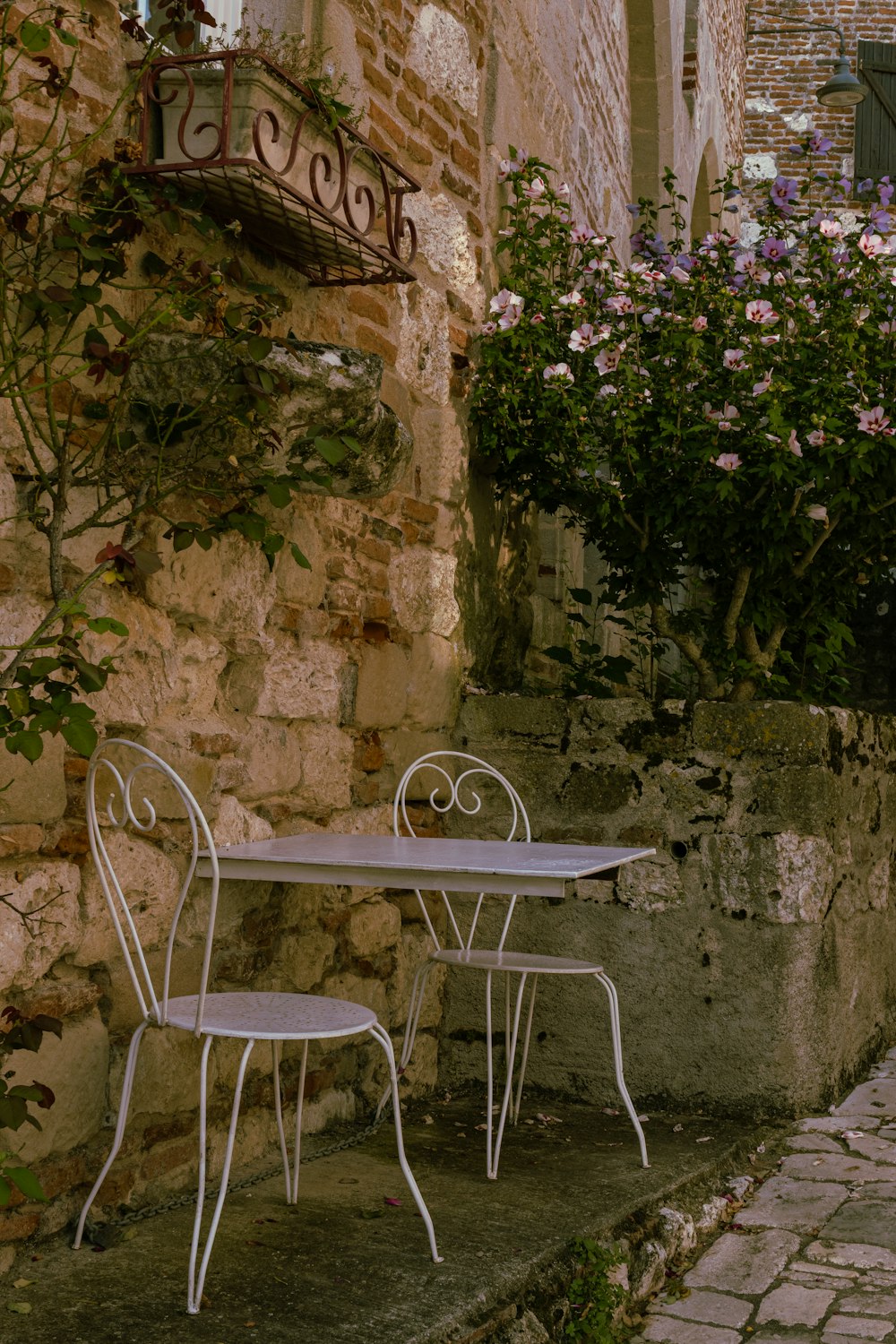 a white table and two chairs sitting on a sidewalk