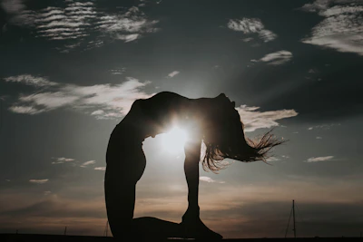 a woman doing a yoga pose in front of the sun