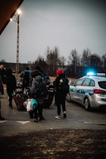 a group of people standing next to a police car