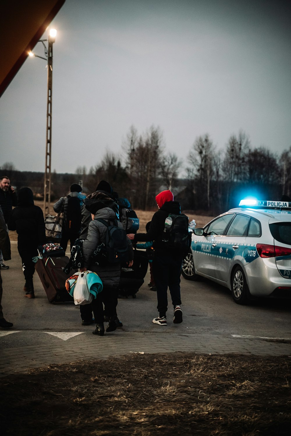 a group of people standing next to a police car