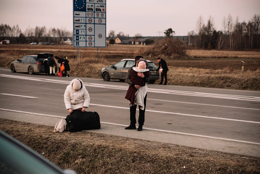 A displaced woman waiting at the roadside with her luggage